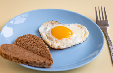 heart shaped scrambled eggs with two halves of heart shaped toast on blue plate, romantic minimalistic design, healthy breakfast for sweetheart
