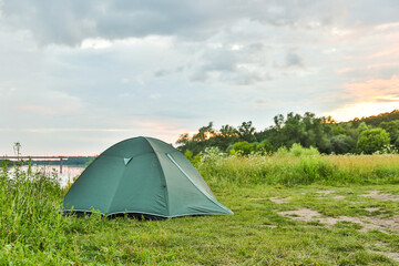 tourist tent is on the bank of the river at sunset