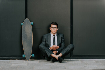 Handsome young business man with his modern longboard