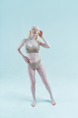 Beauty image of an albino girl posing in studio wearing lingerie. Concept about body positivity, diversity, and fashion - obrazy, fototapety, plakaty