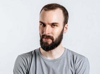 Obraz premium Portrait of a handsome brutal brunette serious man on a white background with crossed arms. The person will soon become the owner of a startup business.