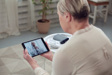 Telemedicine concept. Old woman with tablet during an online consultation with her doctor in her living room
