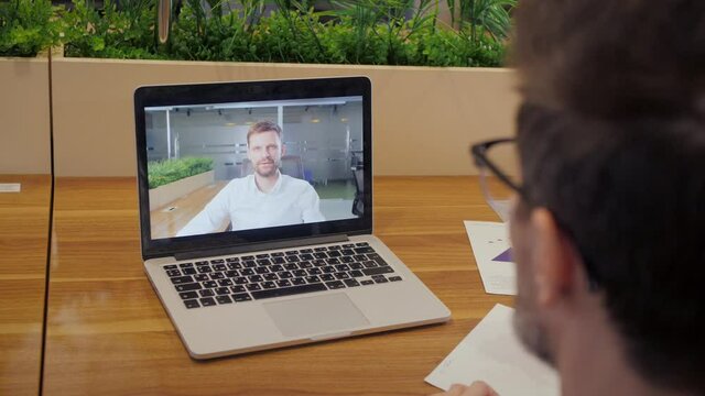 Over shoulder view of male worker have webcam digital virtual conference. Businessman speak talk on video call with manager. Online meeting concept.