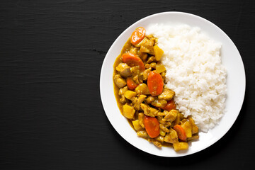 Homemade Japanese Chicken Curry  on a white plate on a black background, top view. Flat lay, overhead, from above. Space for text.