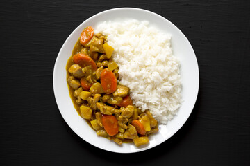 Homemade Japanese Chicken Curry  on a white plate on a black background, top view. Flat lay, overhead, from above.