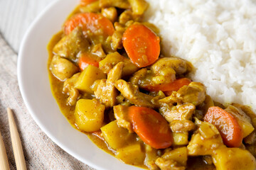 Homemade Japanese Chicken Curry  on a white plate on a white wooden background, side view. Close-up.