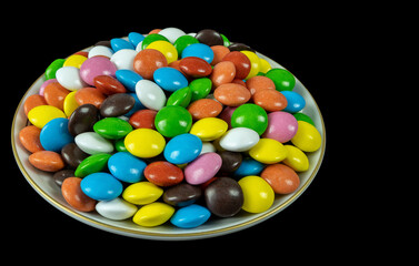 Round milk chocolate balls on a plate on a black background