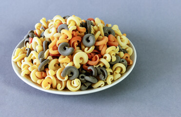 Italian green multicolored pasta with tomato and basil flavor on a gray background