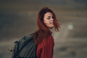 woman with a backpack in a red sweater in the mountains turned back and kapets