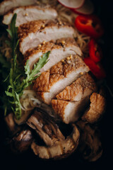 sliced white poultry meat with skin along with noodles, vegetables and arugula. baked duck meat together with pasta top view. ready-made healthy food close-up
