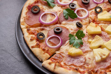 Italian pizza and pizza cooking ingredients on black concrete background. Tomatoes on vine, mozzarella, black olives, herbs and spices. Mixture pizza Italian food. Copy Space. Top view.