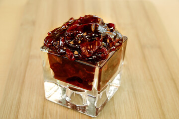 Cherry jam in a glass dish on a wooden table..