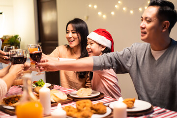 Asian big family clinking wine glasses and enjoying Christmas party.