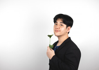 young handsome Asian man in a suit on a white background holds a white rose.