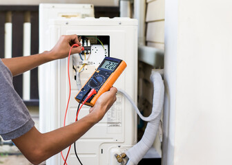 Air repair mechanic using measuring equipment for filling industrial factory air conditioners and...