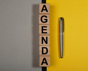 Agenda word on wooden cubes on yellow and gray background
