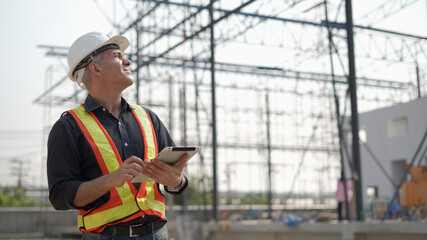 senior construction worker or architect using digital tablet checking structure in construction...