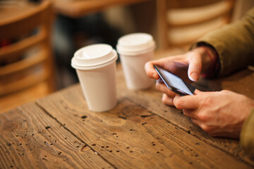 person using a phone next to textured wood and beverages