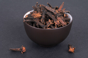 Bol de clous de girofle en gros plan sur fond noir