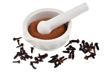 Mortier de clous de girofle en poudre avec un pilon avec des clous de girofle entiers en gros plan sur fond blanc