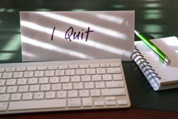 Resignation letter with words I quit on the envelope, in front of computer keyboard on office desk.