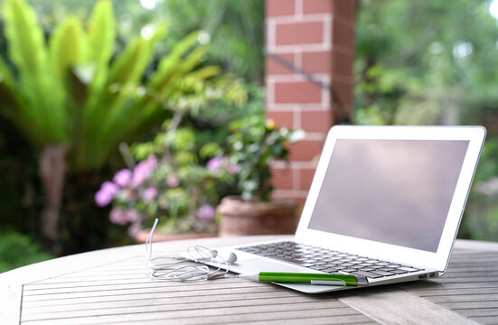 Computer Laptop With Ear Phones On Wood Table At Home Garden. Home Office Concept.