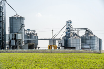 Fototapeta na wymiar Modern Granary elevator. Silver silos on agro-processing and manufacturing plant for processing drying cleaning and storage of agricultural products, flour, cereals and grain. seed cleaning line