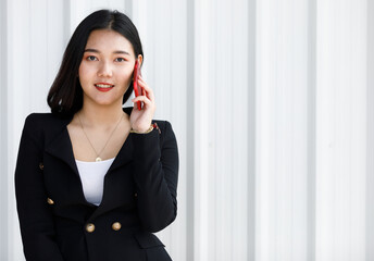 Portrait of Businesswoman standing in black suit. Asian woman holding hand smartphone in white background. Concept beautifull lady working confident.