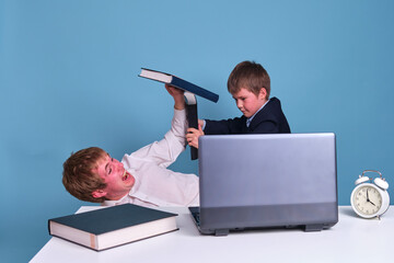 Father and son schoolboy are fighting with textbooks on the background of the table with a...