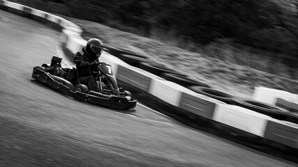 A panning shot of a racing kart as it circuits a track. - obrazy, fototapety, plakaty