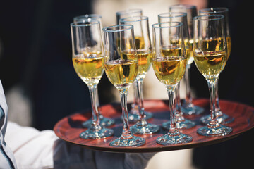 Shallow depth of field (selective focus) details with a waiter walking around and giving sparkling wine to the guests of an event.
