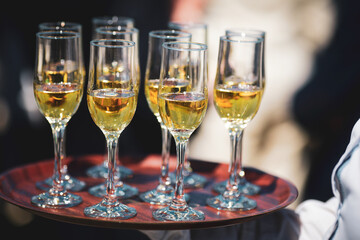 Shallow depth of field (selective focus) details with a waiter walking around and giving sparkling wine to the guests of an event.