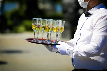 Shallow depth of field (selective focus) details with a waiter walking around and giving sparkling wine to the guests of an event.