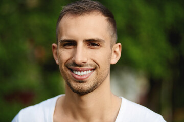 Happy guy in sunglasses posing on a summer day. A handsome young man with a broad smile and...