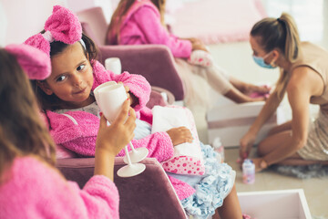 Little girls having part in spa center. Kids are holding a drink glass.