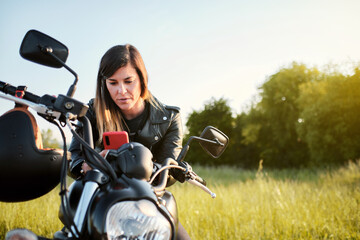 Fototapeta na wymiar young woman using her smart phone while sitting on a motorcycle