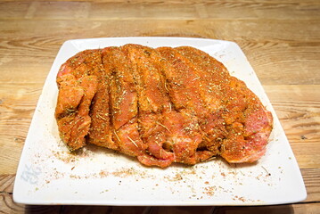 Raw, spiced pork meat on a wooden table in the room 