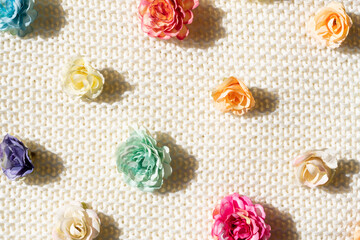 pattern of colorful artificial flowers on a textured beige sweater background