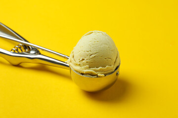 Scoop with ice cream on yellow background