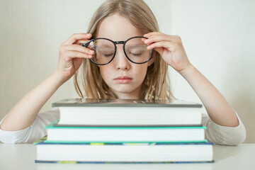 Little girl with glasses does homework, reads books. High quality photo