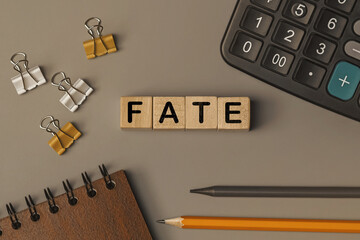 Word - FATE - on small wooden blocks on the desk. Top view
