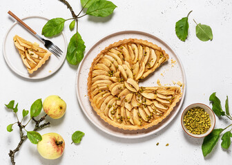 Homemade traditional french baked apple tart with custard filling and green pistachios on a cake pate. Top view. Copy space.