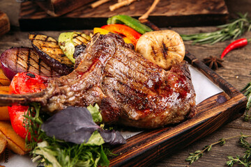 Grilled beef tomahawk steak with vegetables on the wooden background