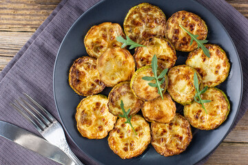Fried slices of zucchini with sour cream sauce. Courgettes with herb for dinner on natural wooden background