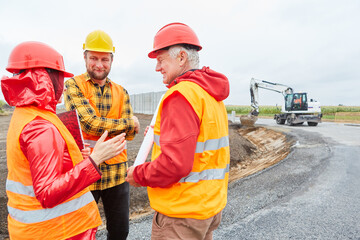 Architect and two construction workers discuss road construction