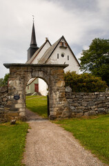 Fototapeta na wymiar Tingvoll Church, Tingvoll, Norway. The 800 years old Romanesque style church is surrounded by a beautiful stone fence with a beautiful stone archway. 