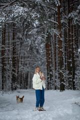Fototapeta na wymiar Blonde young female with ginger white chihuahua and welsh corgi pembroke in a snowy forest in winter