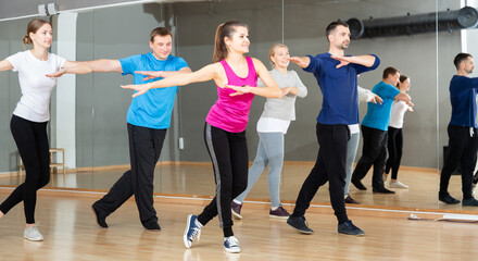 Smiling females and males doing Zumba dance workout during group classes in fitness center
