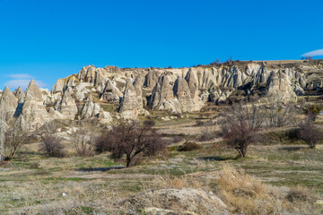Panoramic view of typical landscapes with fairy chimneys, unique rock formations, and fields near Göreme, Cappadocia, Turkey