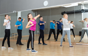 Smiling women and men of different ages warming up during dance class..